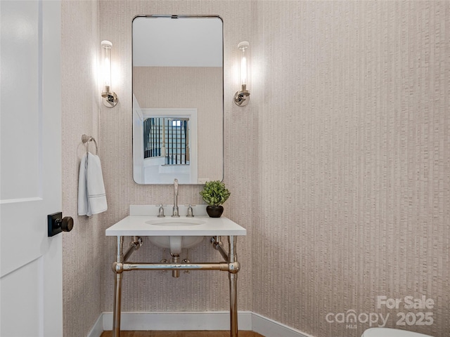 bathroom with wallpapered walls, baseboards, and a sink