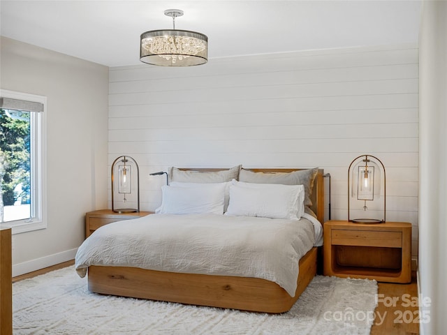 bedroom with a chandelier, baseboards, and wood finished floors