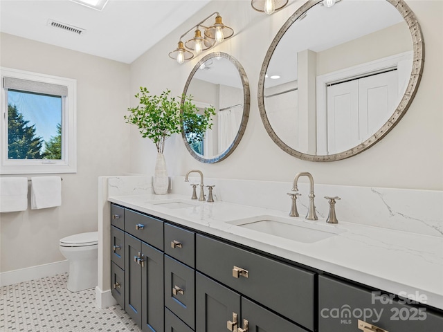 bathroom featuring a sink, visible vents, toilet, and double vanity