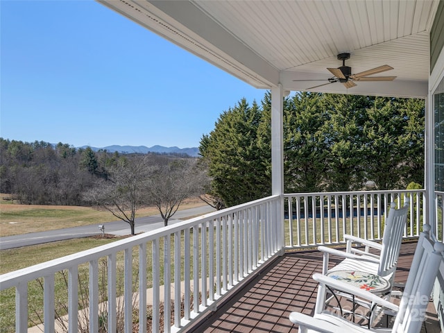 balcony featuring a mountain view and a ceiling fan