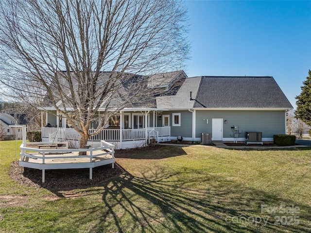 back of property with covered porch, cooling unit, a shingled roof, and a yard