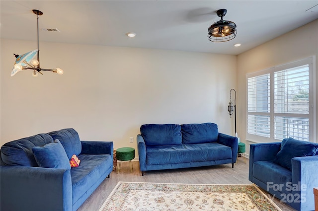 living room featuring a chandelier, light wood-type flooring, visible vents, and recessed lighting