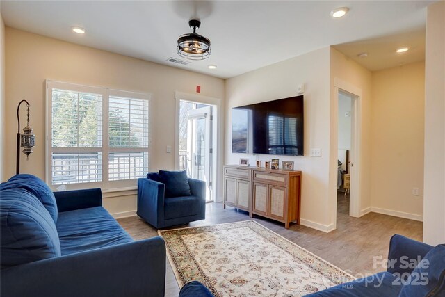 living area featuring baseboards, visible vents, and wood finished floors