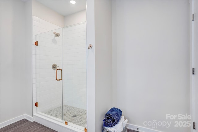 bathroom with a stall shower, baseboards, and wood finished floors