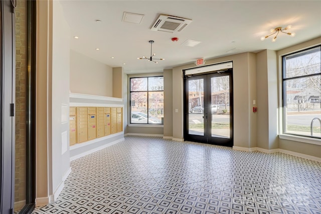 spare room featuring a healthy amount of sunlight, mail area, baseboards, and french doors