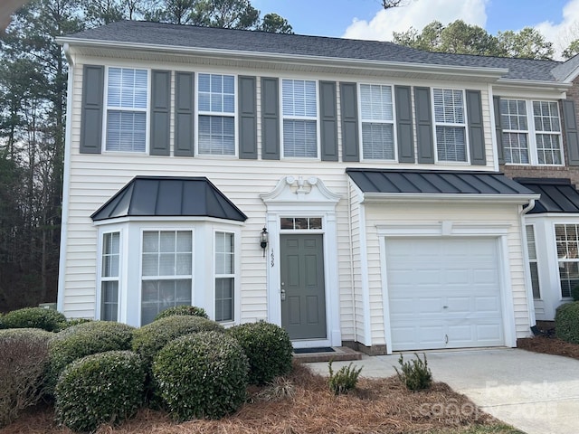 view of front facade with an attached garage, a standing seam roof, metal roof, and concrete driveway