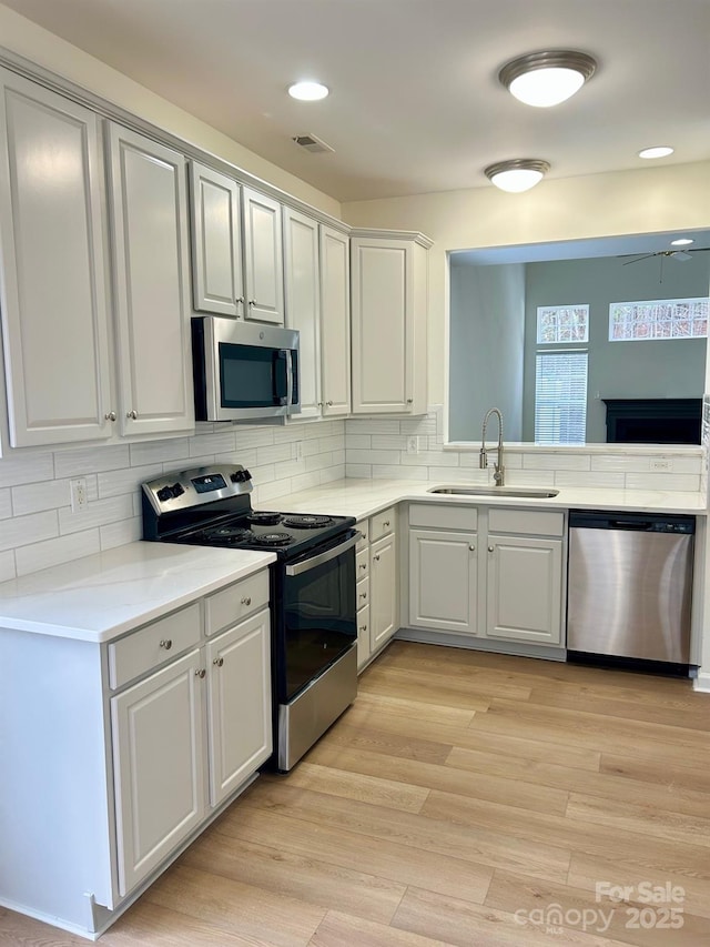 kitchen with tasteful backsplash, visible vents, light wood-style flooring, appliances with stainless steel finishes, and a sink