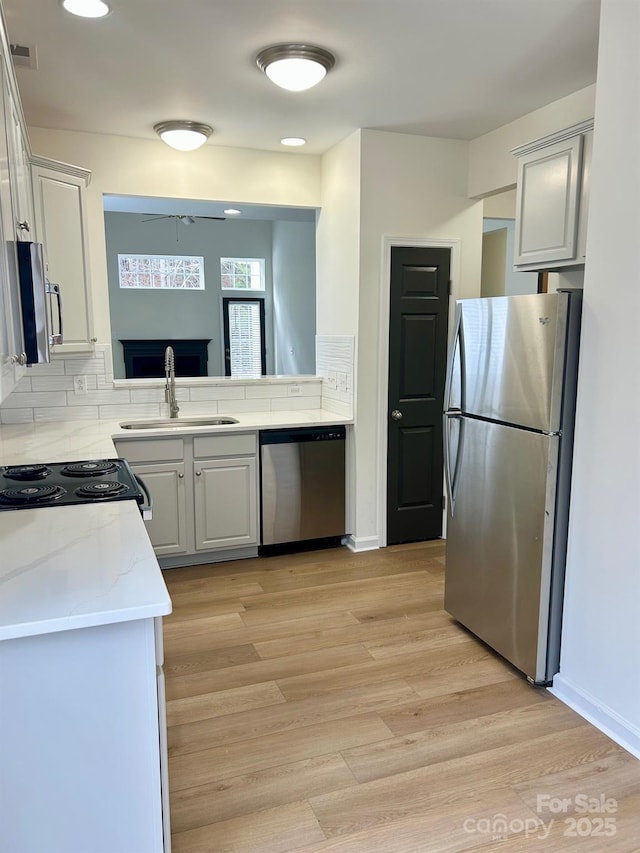 kitchen featuring stainless steel appliances, light wood-style floors, visible vents, and a sink