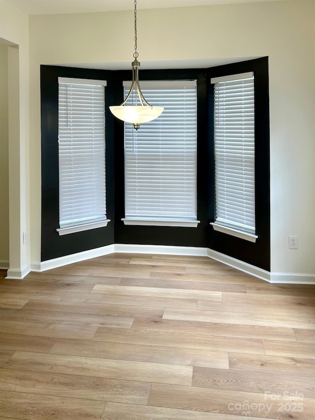 unfurnished dining area with baseboards and wood finished floors