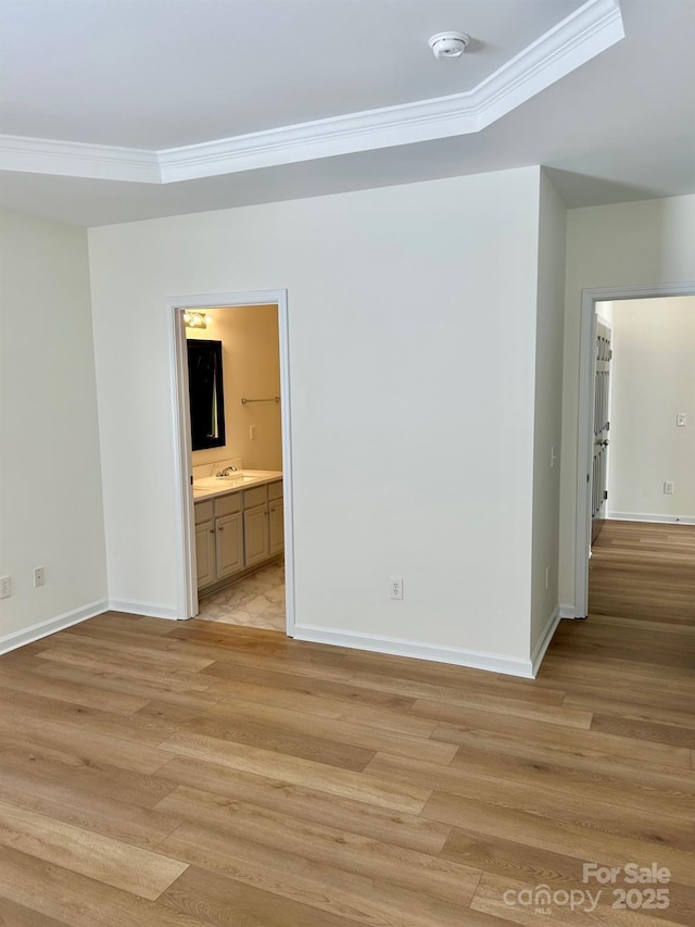 unfurnished room with crown molding, light wood-style flooring, and baseboards