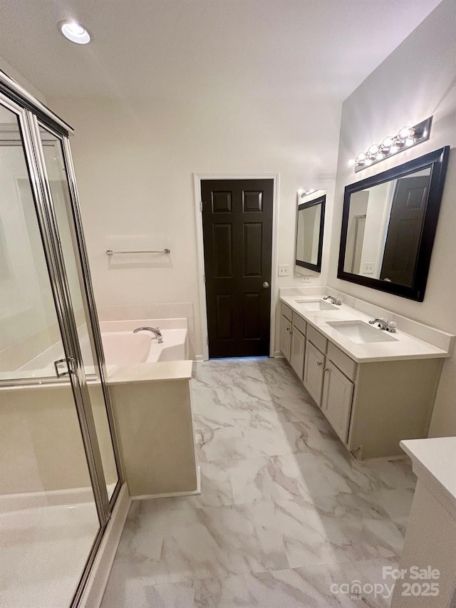 bathroom with marble finish floor, double vanity, a sink, and a bath