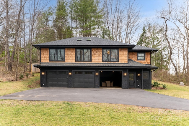 view of front facade with a front lawn, a garage, driveway, and roof with shingles