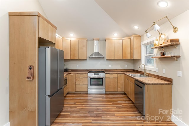 kitchen with light brown cabinets, stainless steel appliances, and wall chimney range hood