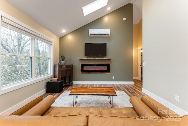 living area with an AC wall unit, a glass covered fireplace, wood finished floors, a skylight, and baseboards