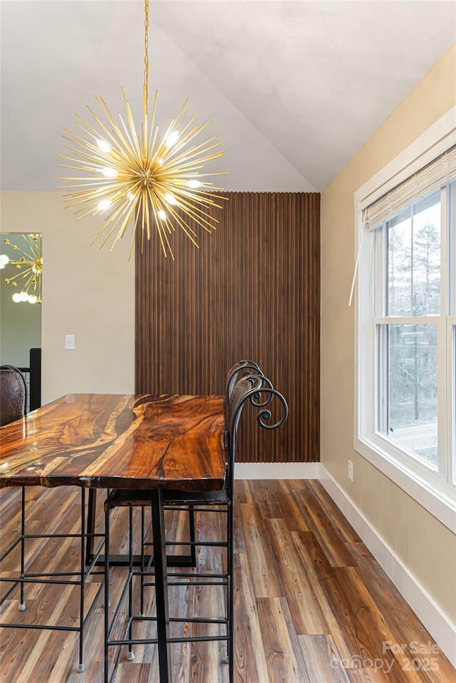 unfurnished dining area with baseboards, an inviting chandelier, and wood finished floors