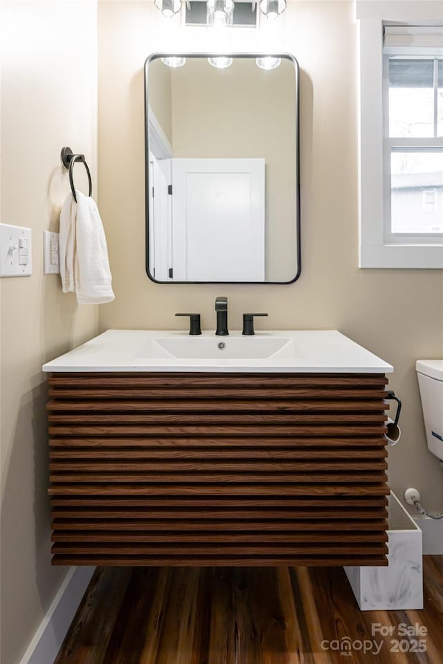 bathroom featuring toilet, wood finished floors, and vanity