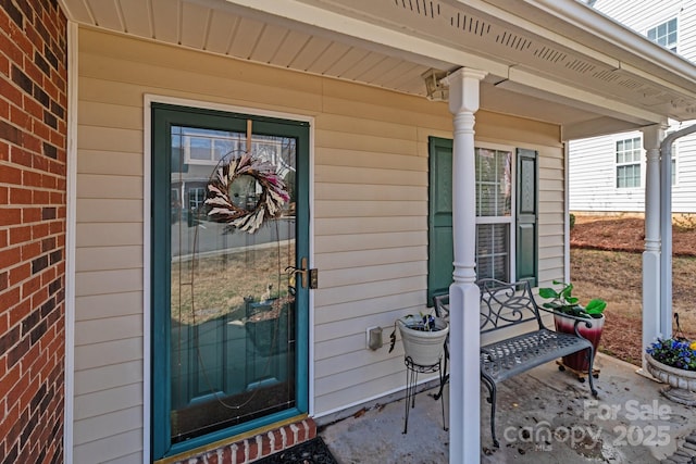 entrance to property featuring a porch and brick siding