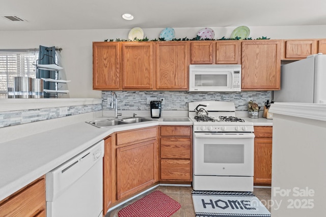 kitchen featuring visible vents, a sink, backsplash, white appliances, and light countertops