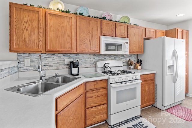 kitchen with tasteful backsplash, white appliances, light countertops, and a sink