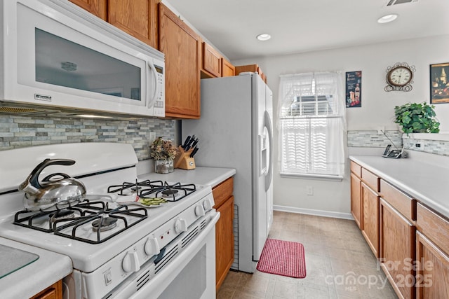 kitchen featuring white appliances, backsplash, brown cabinets, and light countertops