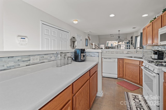 kitchen with a sink, recessed lighting, white appliances, light countertops, and decorative backsplash