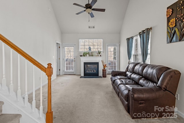 living room featuring stairway, visible vents, carpet floors, and high vaulted ceiling