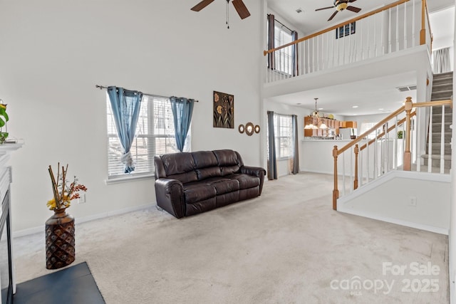 living area with ceiling fan with notable chandelier, stairs, a high ceiling, and carpet floors