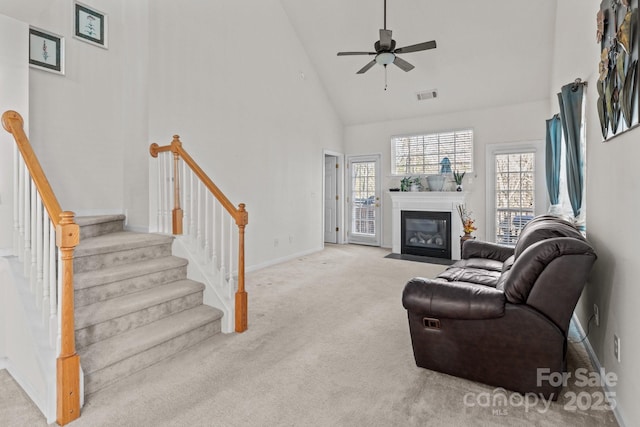 carpeted living room featuring plenty of natural light, visible vents, a fireplace with flush hearth, and high vaulted ceiling