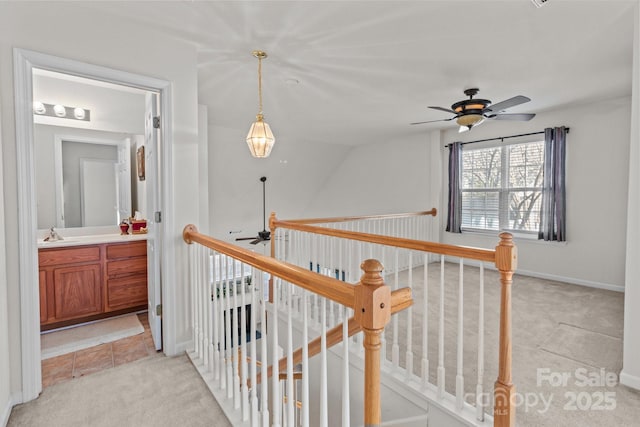 hall featuring an upstairs landing, light colored carpet, and a sink