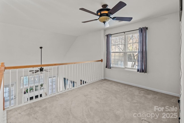 carpeted empty room featuring vaulted ceiling, baseboards, and ceiling fan