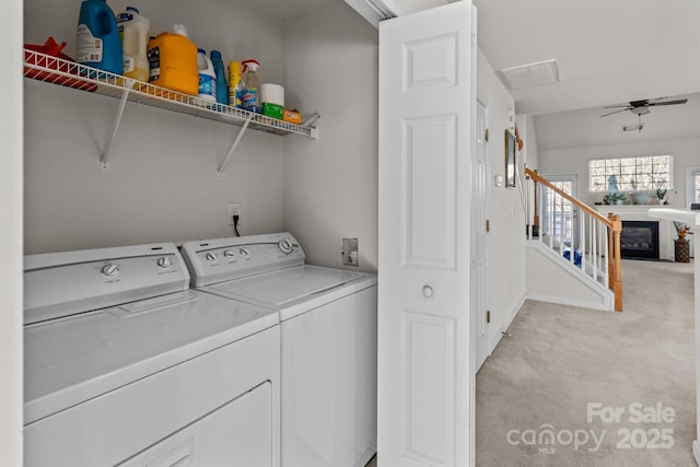 washroom with light carpet, laundry area, a fireplace, a ceiling fan, and separate washer and dryer