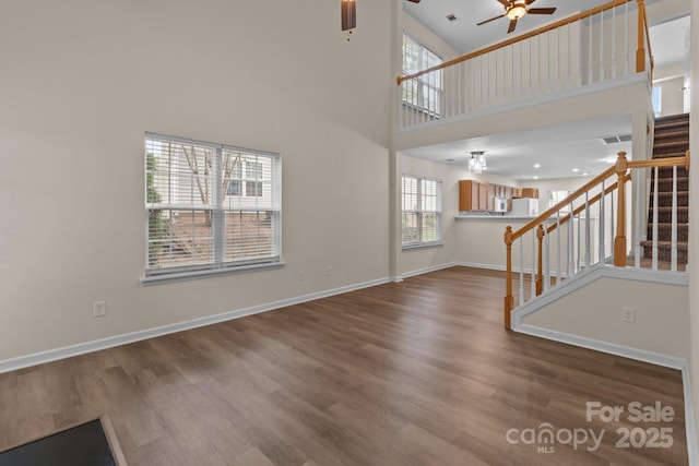 2592 Brackley Pl NW, Concord, NC 28027 - unfurnished living room with a ceiling fan, stairway, healthy amount of natural light, a towering ceiling, and wood finished floors