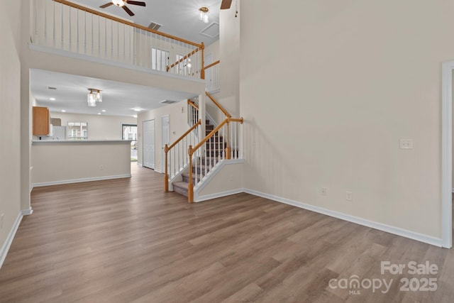 2592 Brackley Pl NW, Concord, NC 28027 - unfurnished living room featuring ceiling fan, wood finished floors, stairway, baseboards, and a high ceiling