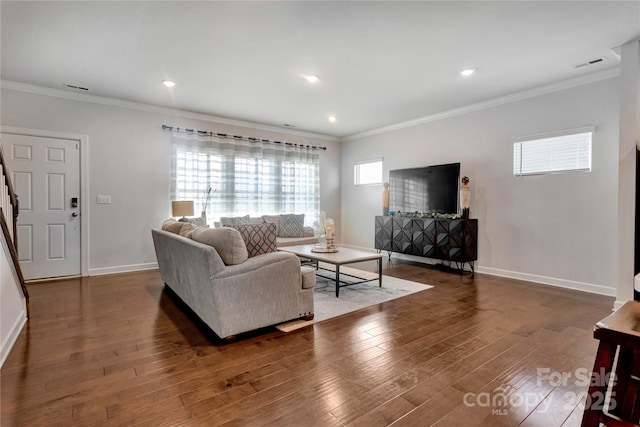 living room with baseboards, visible vents, ornamental molding, and wood finished floors