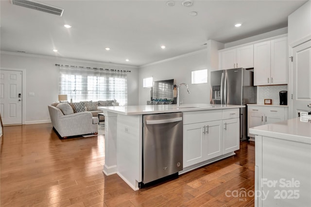 kitchen featuring a sink, visible vents, open floor plan, light countertops, and appliances with stainless steel finishes