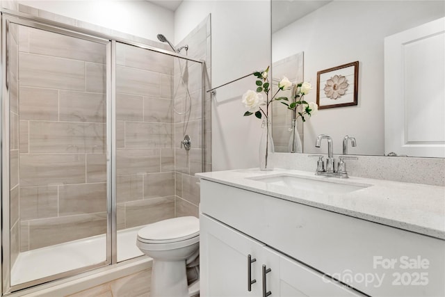 bathroom with a stall shower, vanity, and toilet