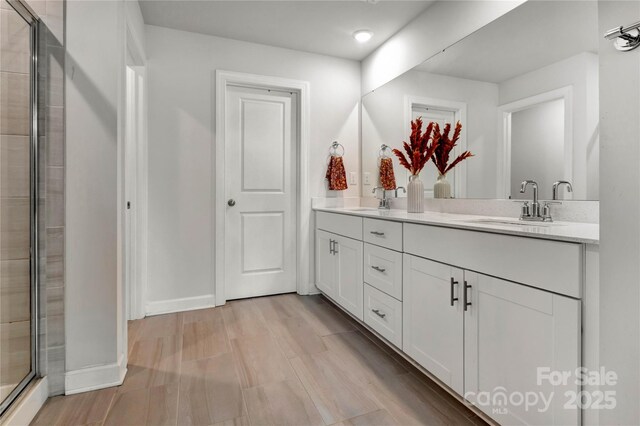 bathroom featuring double vanity, a sink, and a shower stall