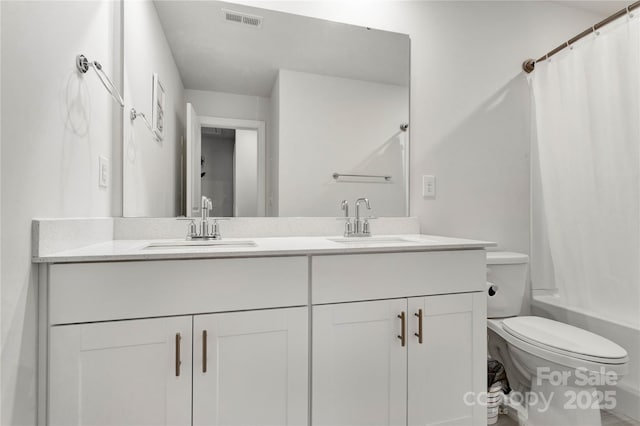 bathroom with toilet, double vanity, a sink, and visible vents