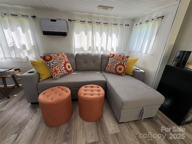 living area featuring a wall unit AC and wood finished floors