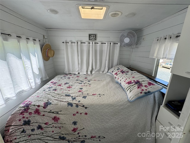 bedroom with multiple windows, visible vents, and wooden walls