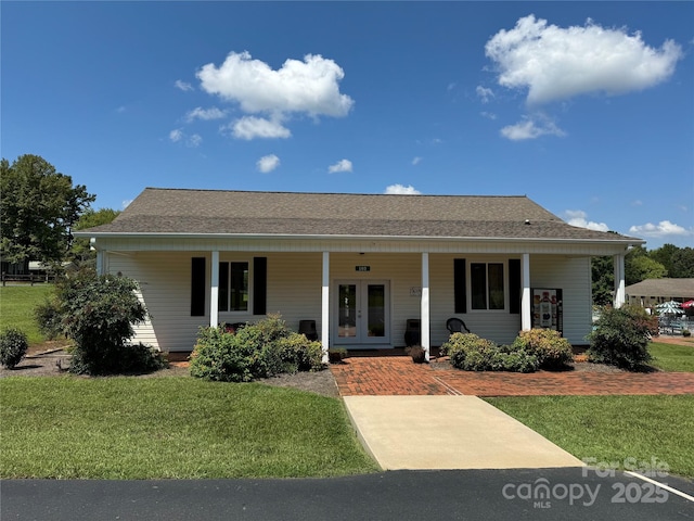 view of front facade featuring covered porch, roof with shingles, french doors, and a front lawn