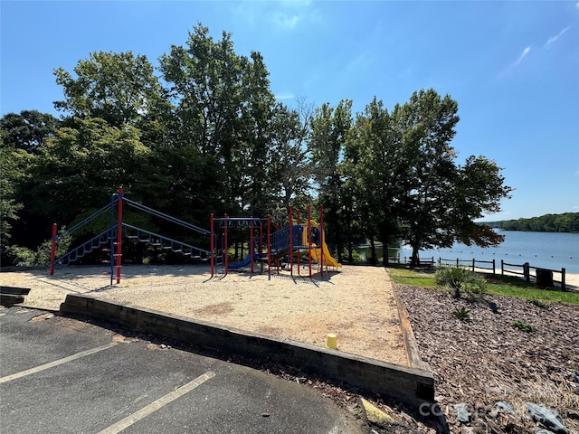 community jungle gym with a water view and fence