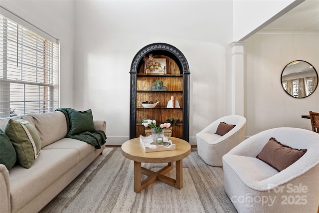 living room with light wood finished floors, decorative columns, and baseboards