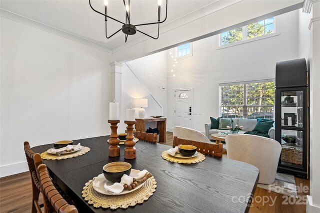 dining space with plenty of natural light, decorative columns, a chandelier, and wood finished floors