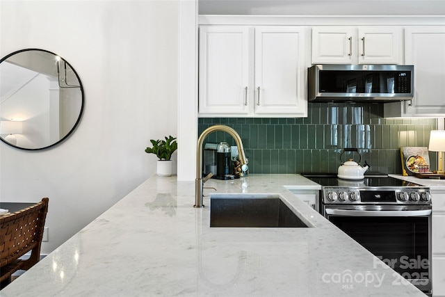 kitchen featuring stainless steel appliances, tasteful backsplash, a sink, and white cabinets