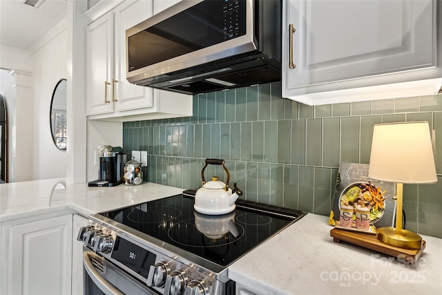 kitchen with light stone counters, appliances with stainless steel finishes, white cabinets, and decorative backsplash