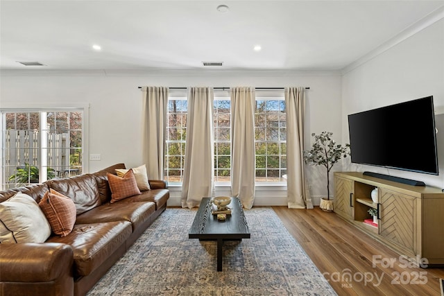 living area with recessed lighting, wood finished floors, visible vents, and crown molding