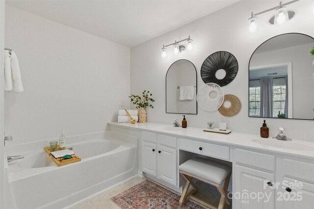 bathroom with double vanity, tile patterned flooring, a sink, and a bath