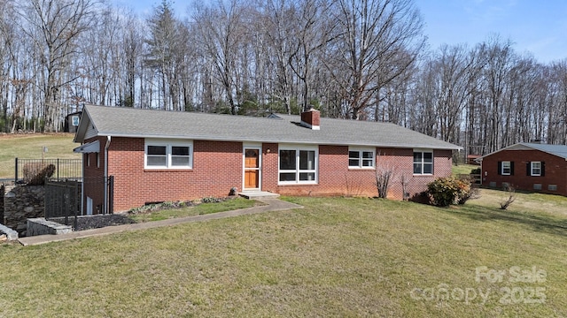 ranch-style house with roof with shingles, brick siding, a chimney, and a front yard