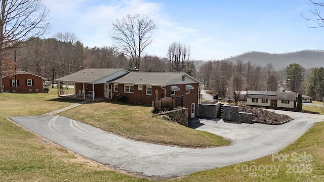 view of front of house with covered porch, central AC, brick siding, driveway, and a front yard